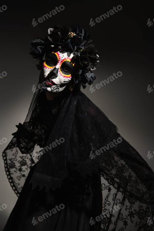 Preview: Woman with catrina makeup and dark wreath on head looking at camera on black background
