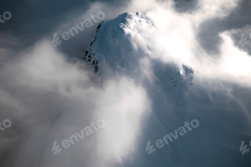 Vorschau: Luftaufnahme eines Berggipfels inmitten der Wolken