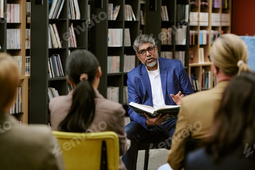 Preview: Middle Aged Man Leading Book Presentation to Diverse Adult Audience