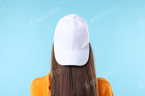 Preview: Woman in stylish baseball hat on light blue background, back view