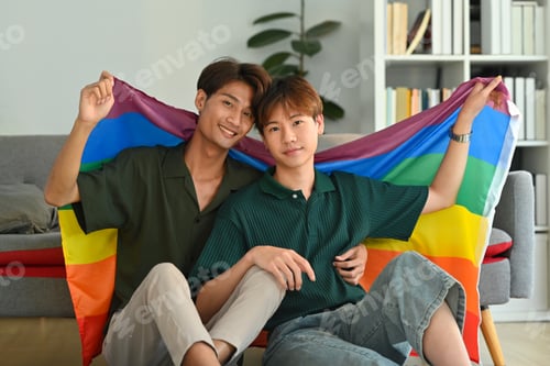 Preview: Image of gay couple embracing under LGBT pride flag. LGBT, love and human rights concept.