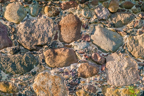 Preview: gray wall surface of old stones with plaster in cracks in the rays of the evening sun