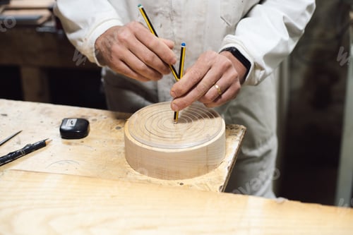 Preview: Cabinetmaker marking the center of a wooden circle with a pencil in his workshop
