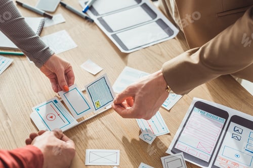 Preview: Cropped view of creative designers planning mobile app interface at table
