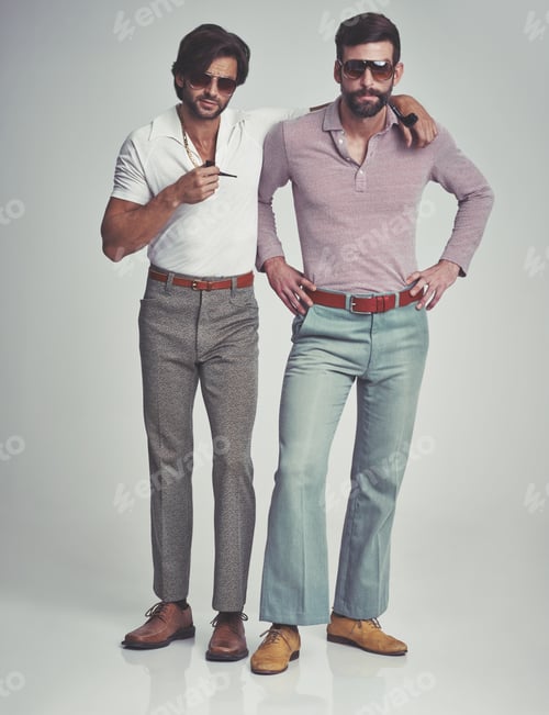 Preview: Studio shot of two men standing together while wearing retro 70s wear and smoking pipes