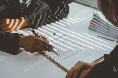Preview: Human resources manager pointing at a resume with a pen while conducting an interview with a candida