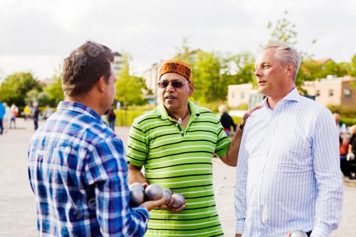 Preview: Male friends talking while playing boule in park