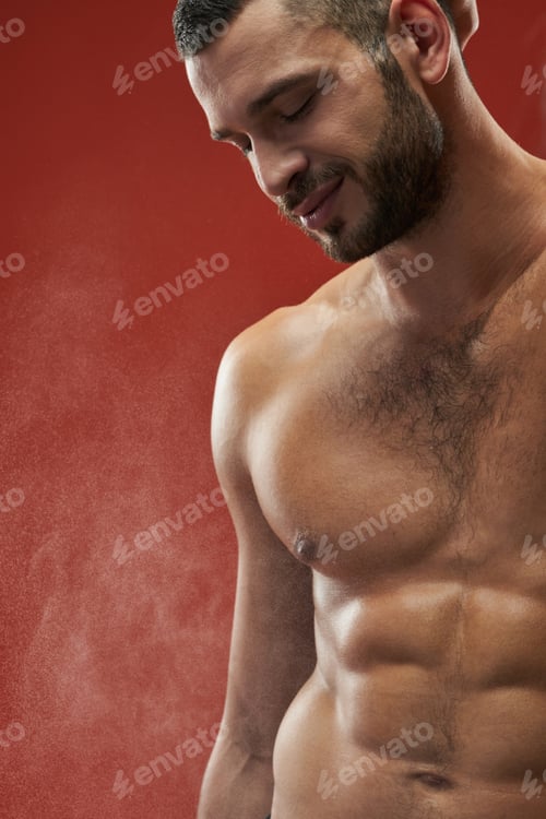 Preview: Happy smiling athlete man showing his embossed body in the indoors