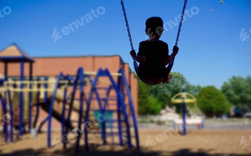 Preview: Boy riding swing at playground looking at kite
