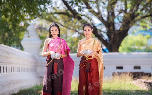 Preview: Asian woman wearing ancient Thai traditional dress holds garland and fresh flowers paying homage Bud