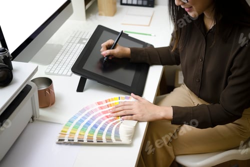 Preview: Cropped shot of smiling graphic designer working with graphic tablet and color swatch.