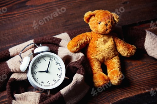 Preview: Scarf and alarm clock with teddy bear on wooden table