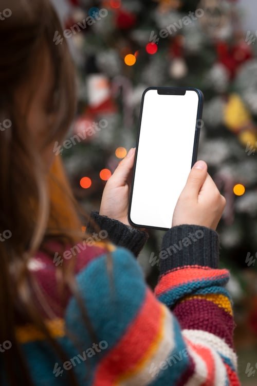 Preview: Girl holding a smart phone with the Christmas tree in the background