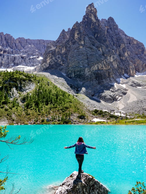 Preview: Young woman standing on a rock by a lake, view, mountain peak.