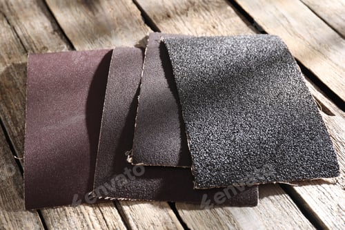 Preview: Many coarse sandpapers on wooden table, closeup