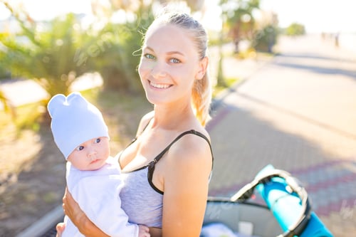 Preview: happy blonde woman kissind and feelinf adore to her stroll new born kid in tropics