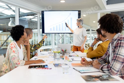 Preview: Mature Caucasian businesswoman giving presentation on screen during meeting