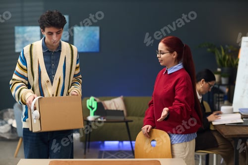 Preview: Young Man Packing Office Belongings While Young Woman Gesturing