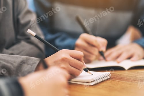 Preview: Closeup image of many people writing on blank notebook together on wooden table