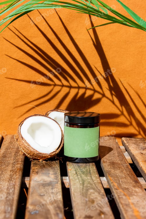 Preview: coconut and a jar of cream on a wooden table with a palm tree in the background