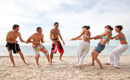 Preview: Group Of Friends Competing Pulling A Rope At The Beach - Men Against Women