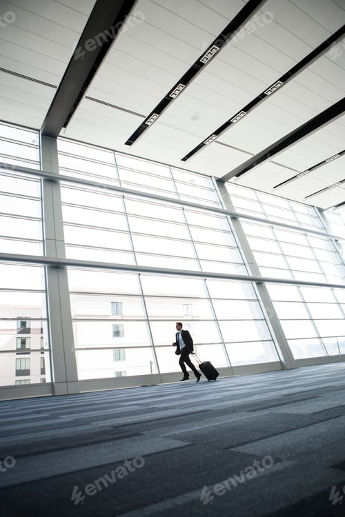 Preview: Bussinessman running past a window in the lobby of a conference centre.