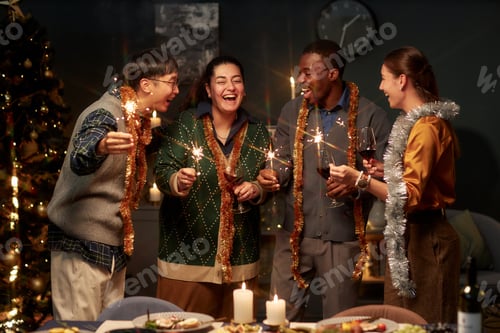 Preview: Smiling Friends in Vintage Clothes holding Sparklers while Celebrating Christmas at Home