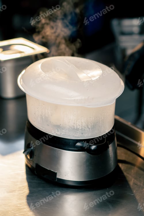 Preview: steamer which buns are being processed stands on the table for cooking there are utensils around