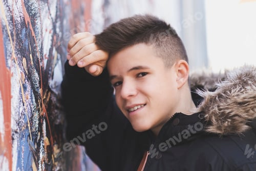 Preview: Portrait of teenager leaning against a wall in the street, looking at the camera.