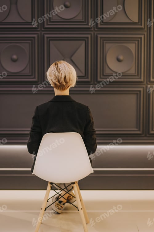 Preview: Girl sitting on a chair against a dark wall