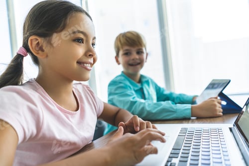 Preview: The happy girl and a boy sitting at the table with a laptop and a tablet