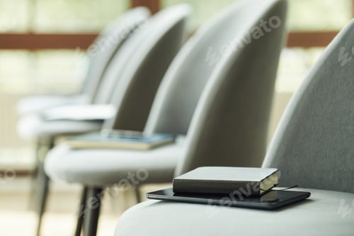 Preview: Stack of Books and Digital Tablet Resting on Empty Chairs in Waiting Room
