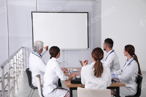 Preview: Team of doctors using video projector during conference indoors