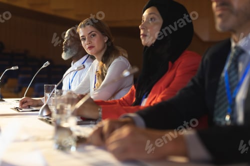 Preview: Businesswoman looking at camera while business colleague sitting together in the auditorium