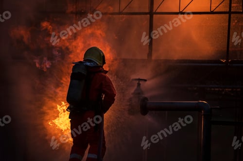 Preview: Firefighter in the training with fire hose nozzle spraying high pressure water to fire