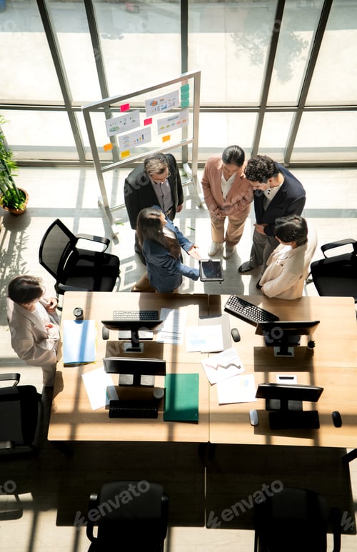 Preview: Multicultural business team standing around a desk and reviewing information on a tablet