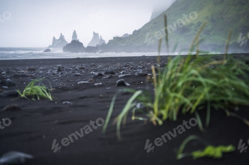 Preview: Black beach in Vik with famous Reynisdrangar rock formations and the mount Reynisfjall in stormy
