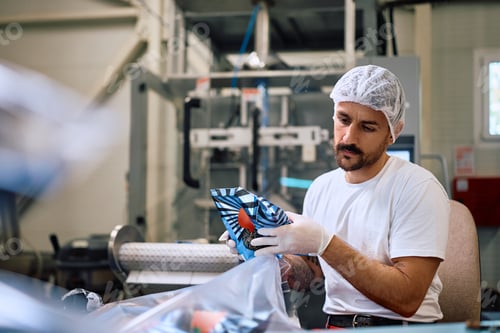 Preview: Factory employee packing processed food while working in production facility.