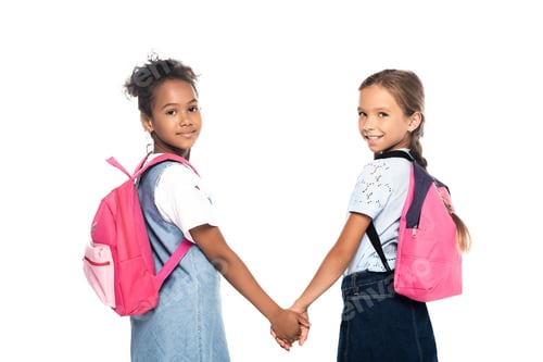 Preview: multicultural friends with backpacks holding hands and looking at camera isolated on white