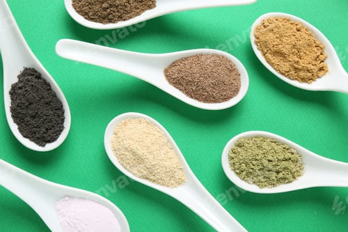 Preview: Different superfood powders in spoons on green background, flat lay