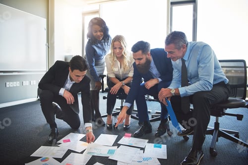 Preview: Work colleagues brainstorming with paperwork on an office floor
