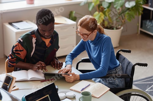 Preview: Young woman with disability talking to colleague during business meeting