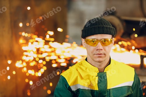 Preview: Portrait of man worker Engineer Wearing protective glasses factory background with flying sparks