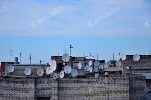Preview: A lot of satellite television antennas on the rooftop under a blue sky