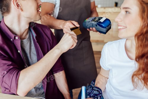 Preview: cropped shot of smiling young couple with credit card looking at smiling waiter with payment