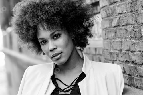 Preview: Close-up portrait of black woman with afro hairstyle standing in urban background. Mixed girl