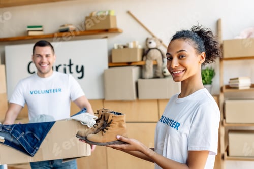 Preview: selective focus of pretty african american volunteer holding kids shoes near handsome man with