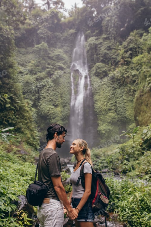 Preview: Couple in love standing near a waterfall in forest