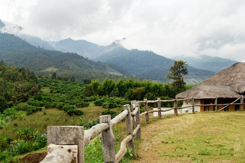 Preview: Scenic landscape on the mountains, wooden fence on foreground and houses on background