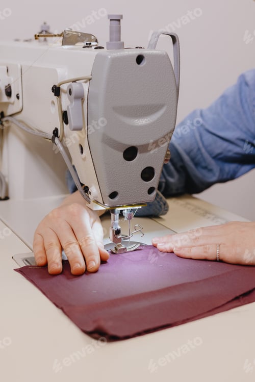 Preview: woman sews piece of cloth on sewing machine. industrial metal machine for all fabric tops.